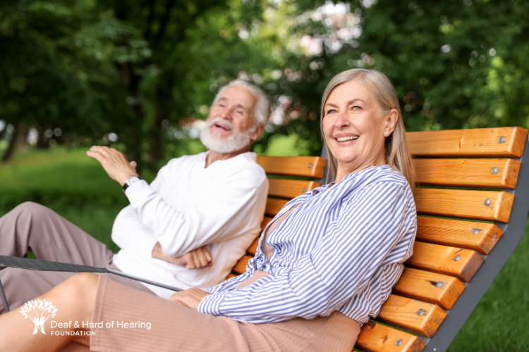 Two elderly people sitting on a bench outside